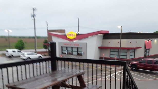 A picnic table with benches, a fenced area, and a building with a 'Penny's' sign. - Italy Inn (Italy)
