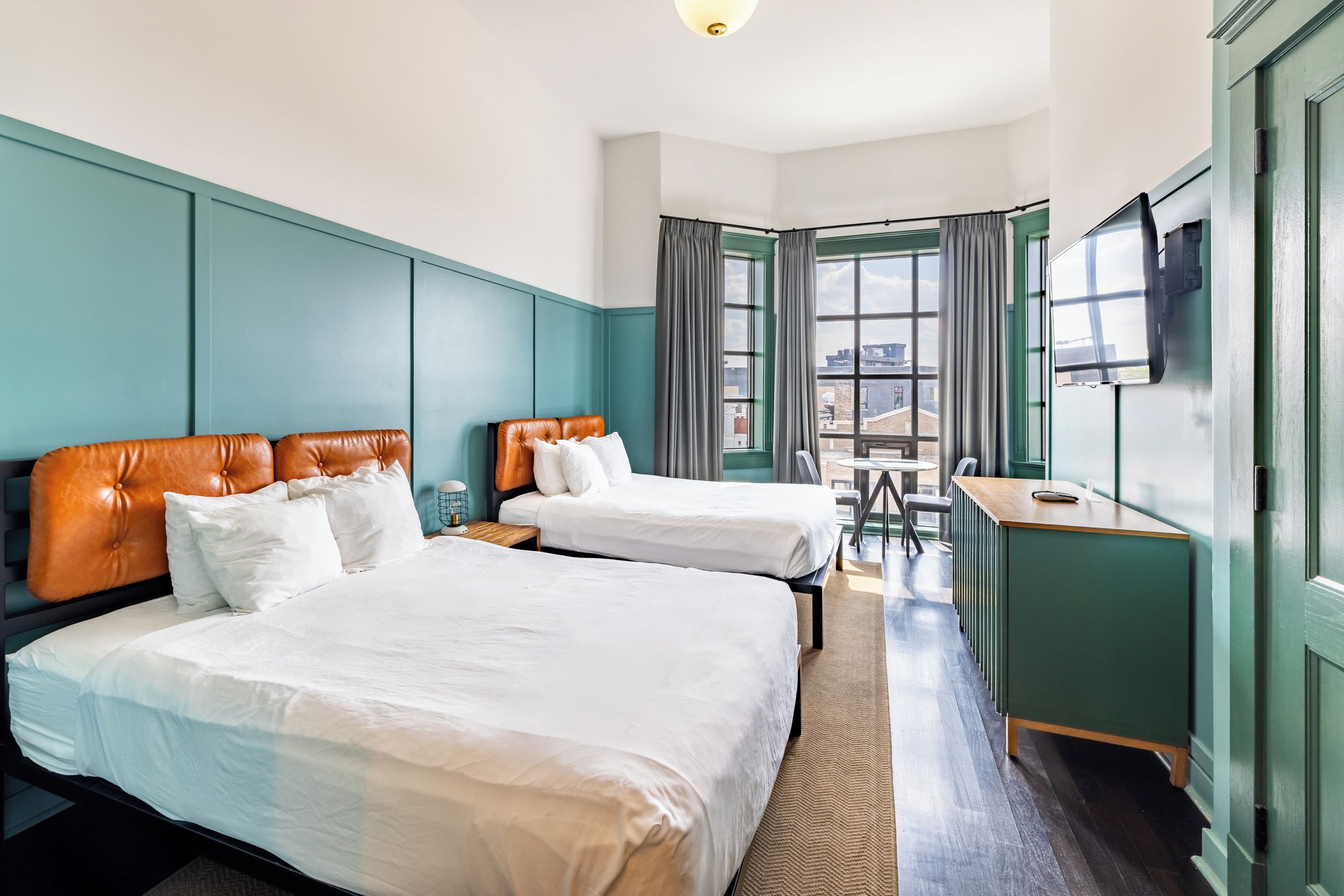 Une chambre d’hôtel avec deux lits, un bureau et une tél évision.