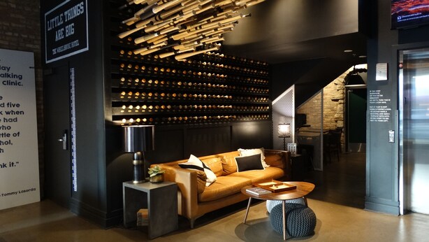A modern interior with a sofa, a coffee table, and a wall of wine bottles. - The Chicago Hotel Collection - Wrigleyville (Chicago)
