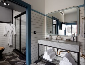 A modern bathroom with a large mirror, a marble sink, and a glass-enclosed shower.