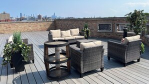 A rooftop patio with wicker furniture, a round table, and potted plants. - The Chicago Hotel Collection - Wrigleyville (Chicago)