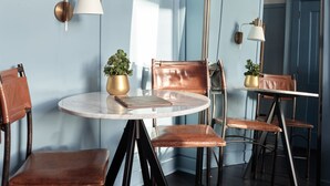 A room with a round table, four chairs, two wall-mounted lamps, and a large mirror. - The Chicago Hotel Collection - Wrigleyville (Chicago)
