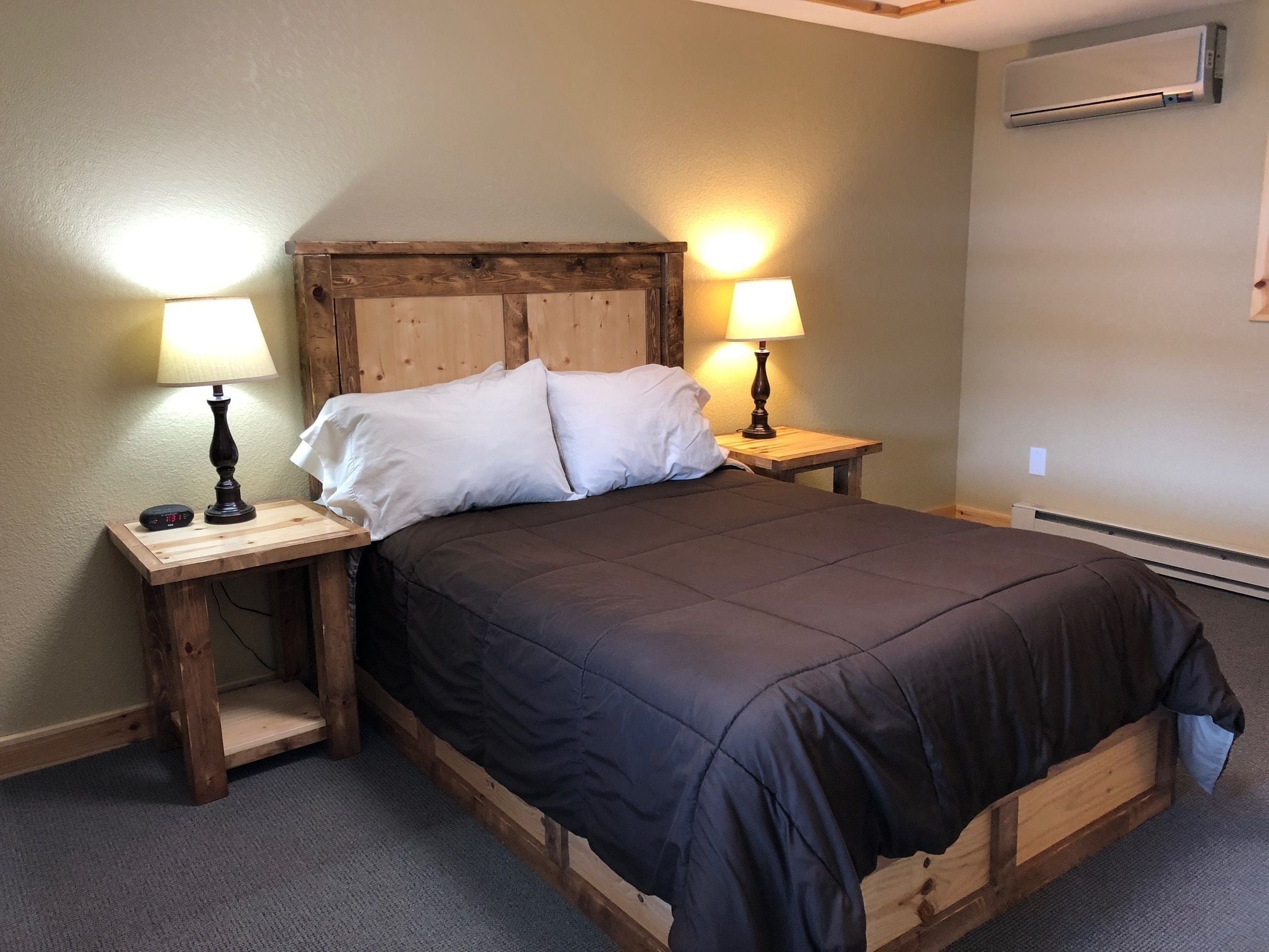 Una cama individual con cabecera de madera y dos mesitas de noche, cada una con una lámpara.