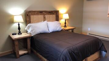 Una cama individual con cabecera de madera y dos mesitas de noche, cada una con una lámpara.