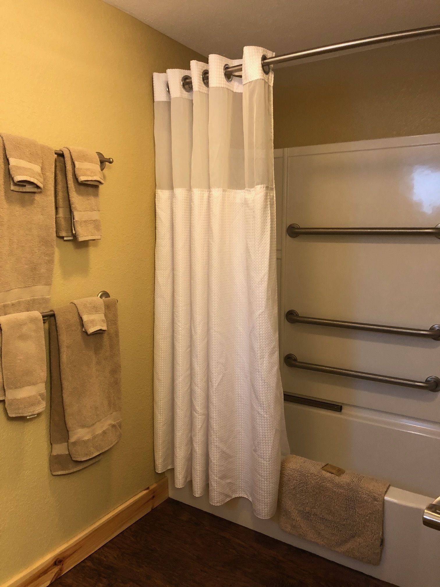Een badkamer met douchegordijn, handdoekhouders en een bad.