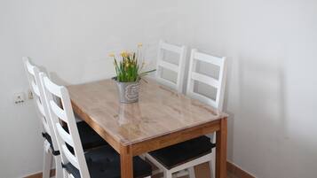 Een eettafel met vier witte stoelen, een welkomstbord en een stadsgezicht poster aan de muur.