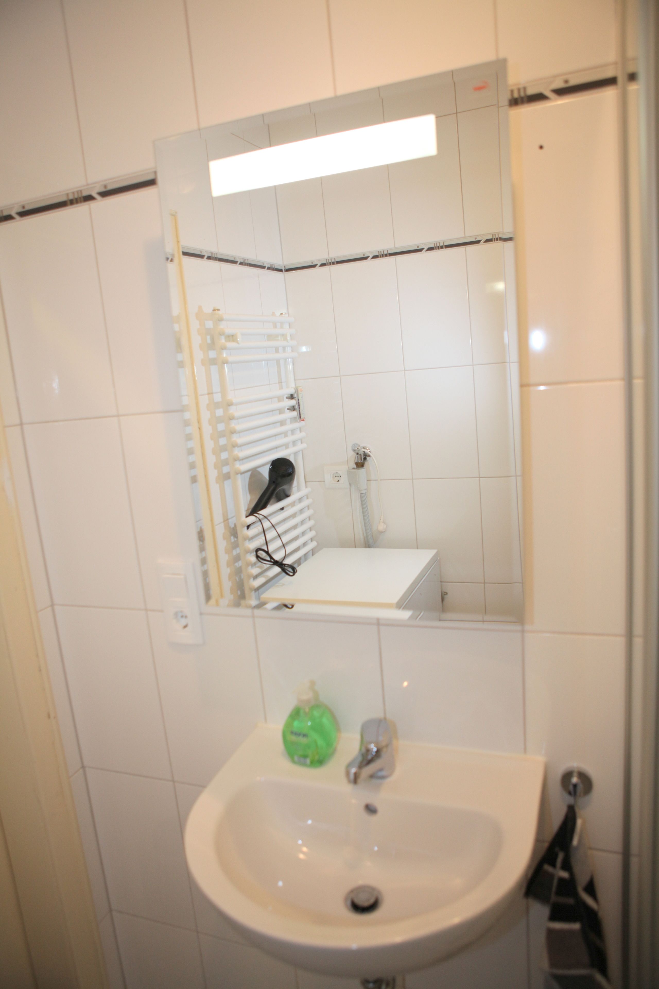 Une salle de bain avec un lavabo blanc, un miroir et un porte-serviettes.