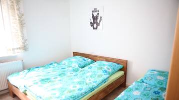A small, tidy bedroom with a single bed, a wooden headboard, and a poster on the wall.
