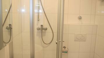 A bathroom with a glass-enclosed shower, a sink, and a toilet.