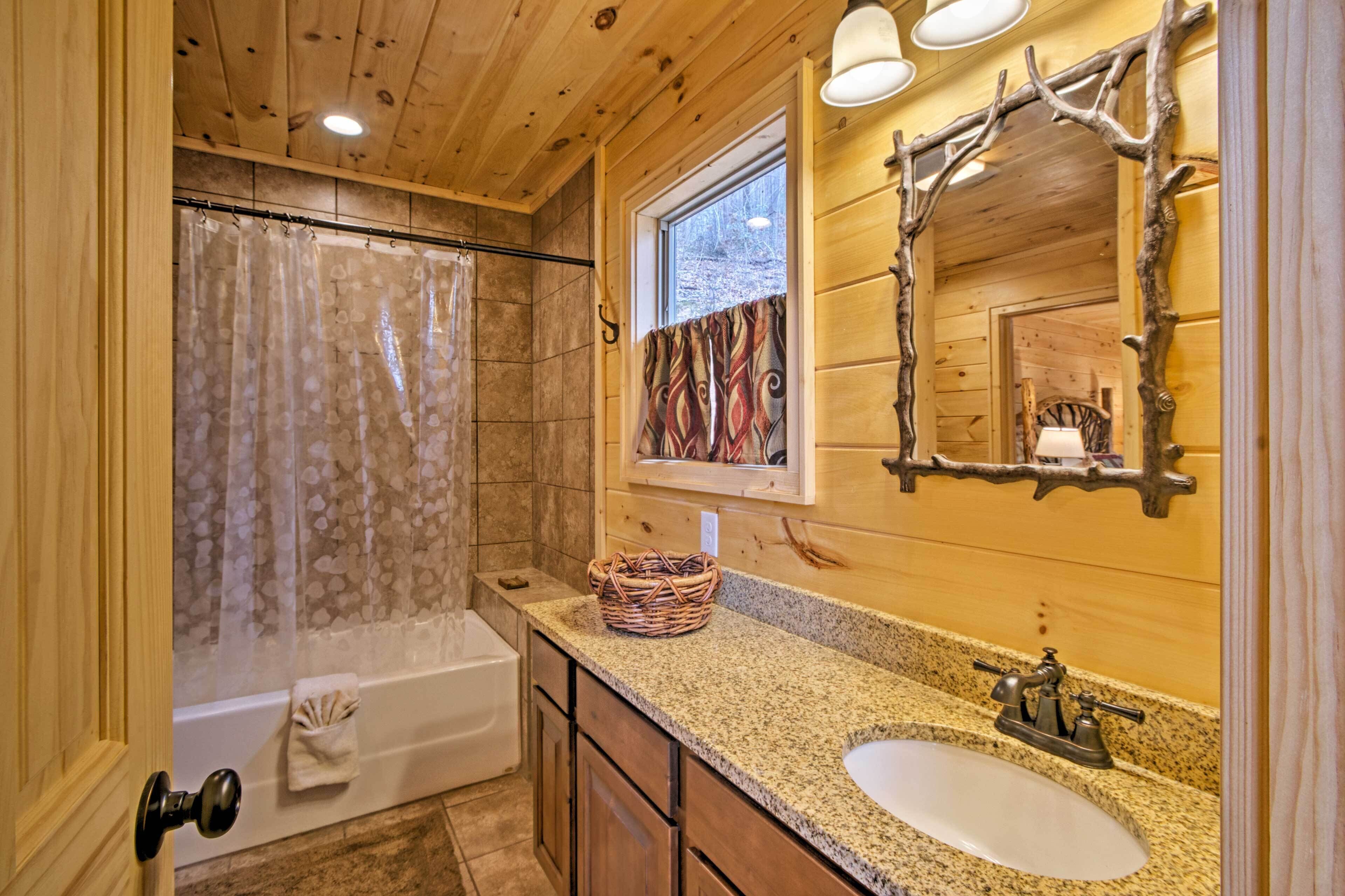 A wooden cabin bathroom with a shower, a sink, and a mirror.