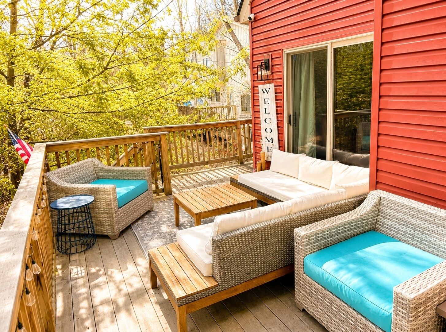 A deck with wicker furniture, a small table, and a welcome sign.