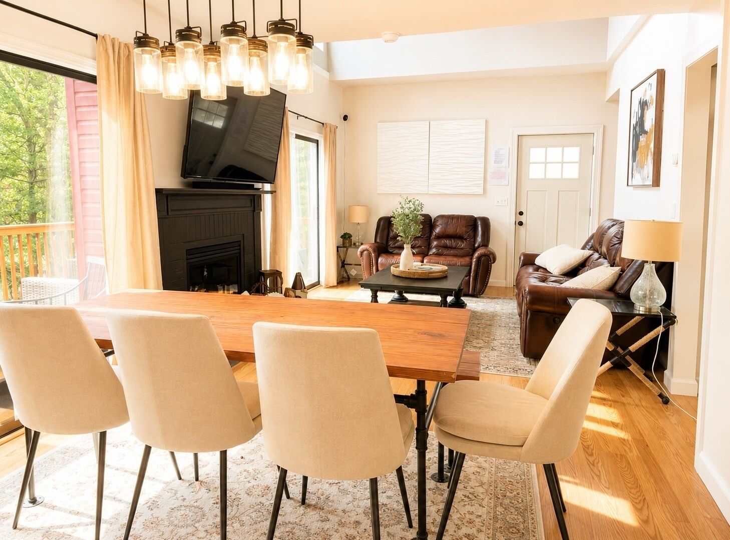 Een moderne woonkamer met een open haard, leren banken, een eettafel met stoelen en een groot raam.