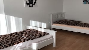 Una habitación con dos camas individuales, cabecera blanca, colcha marrón estampada y una pared con un cartel que dice 'BIG BOSS'.