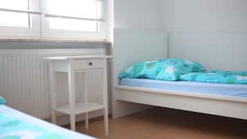 Ein Zimmer mit einem Einzelbett, einem kleinen weißen Schreibtisch und einer Heizung.