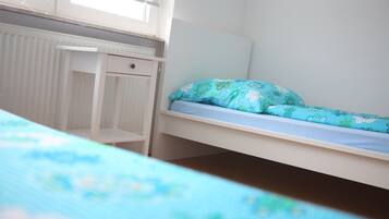Una camera da letto per bambini con un letto a castello, una scrivania e un termosifone.
