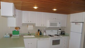 A compact kitchen with white cabinets, a microwave, stove, and refrigerator. - 13 on the beach 10, Ocean City, MD, USA - Beautiful direct ocean front 3 bedroom 2 bath townhome (Ocean City)