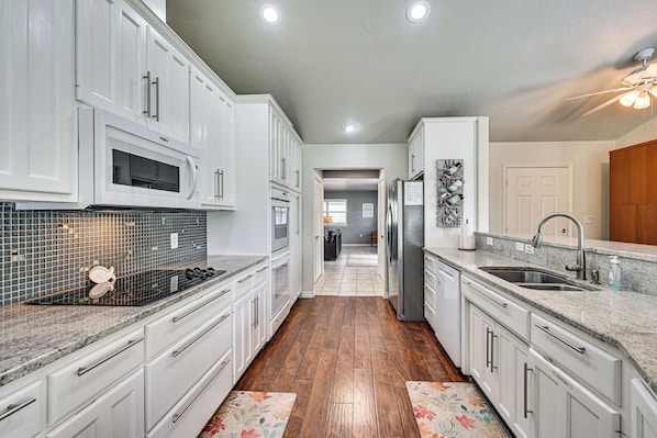 A kitchen with white cabinets, a microwave, a refrigerator, and a sink.