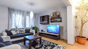 A modern living room with a sofa, coffee table, TV, and decorative items including a ship model.