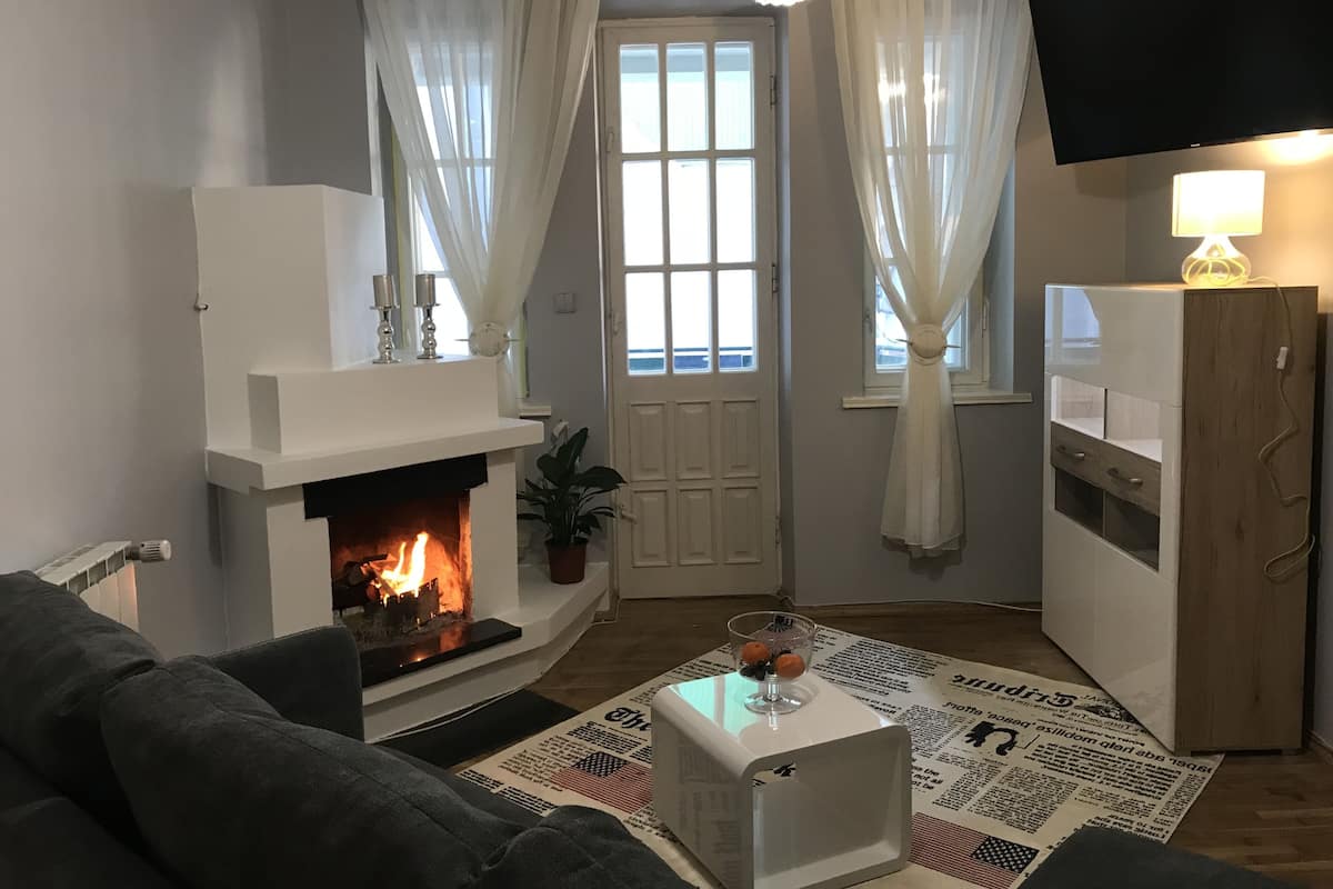 Una sala de estar con chimenea, televisor y sofá.