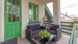 A covered outdoor seating area with wicker furniture and a green door.