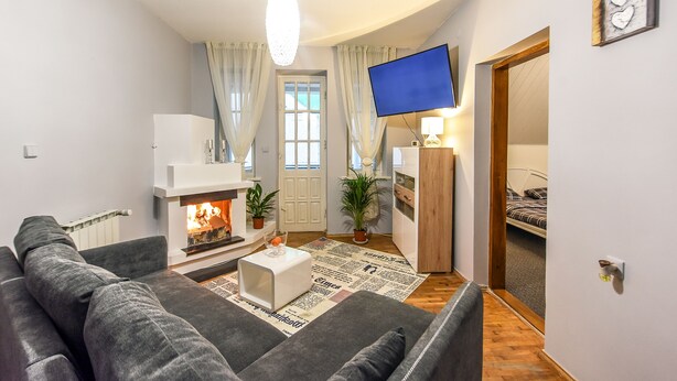 A cozy living room with a fireplace, a flat-screen TV, and a comfortable sofa.