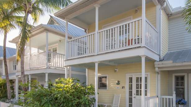 A two-story house with a balcony, a porch with a rocking chair, and a white picket fence. - Amberjack at The Truman Annex in Key West (Key West)