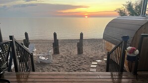 A wooden deck leading to a beach with a sunset view.