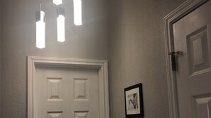 A hallway with a white door, a light fixture above, and two framed pictures on the wall. - Spacious home near all San Antonio Attractions! Karaoke Machine is available (San Antonio)