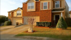 A two-story house with a garage, a well-maintained lawn, and a small tree in the front yard. - Spacious home near all San Antonio Attractions! Karaoke Machine is available (San Antonio)
