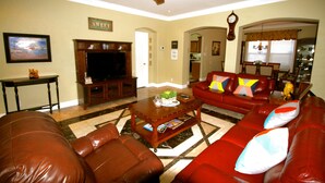 A living room with a red sofa, a wooden coffee table, a television, and a ceiling fan. - Spacious home near all San Antonio Attractions! Karaoke Machine is available (San Antonio)