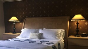 A neatly made bed with white linens and a decorative headboard. There are two bedside tables with lamps on either side of the bed. - Spacious home near all San Antonio Attractions! Karaoke Machine is available (San Antonio)