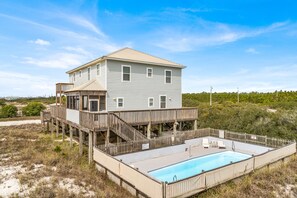 Ein zweistöckiges Strandhaus mit Holzterrasse und Schwimmbecken.