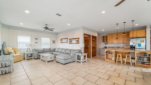 A spacious living room with a sectional sofa, a dining area with a kitchen counter, and a ceiling fan. - Large 6 Bdrm home with amazing Gulf Views, Easy Beach Access, and Private Pool (Gulf Shores)