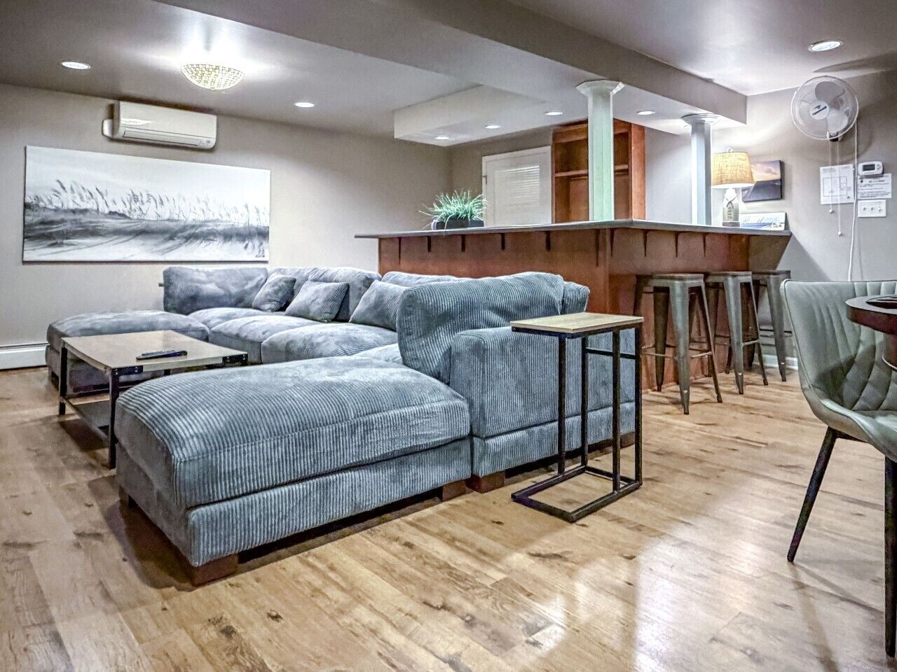 A modern living room with a sectional sofa, a small table, and a bar area with stools.