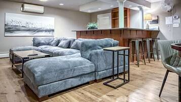 A modern living room with a sectional sofa, a small table, and a bar area with stools.