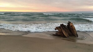 A beach with a large rock formation in the foreground and waves crashing onto the shore. - Panoramic views, Hot Tub, Sauna, Firepit, Sand Vball, Foosball, Dunes Nat`l Park (Miller Beach)