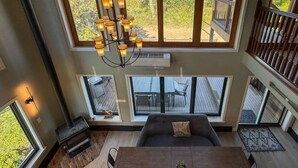 A spacious room with a large wooden table, comfortable seating, and multiple windows offering views of the outdoors. - Panoramic views, Hot Tub, Sauna, Firepit, Sand Vball, Foosball, Dunes Nat`l Park (Miller Beach)