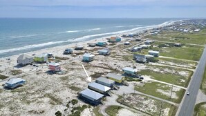 An aerial view of a coastal area with buildings, a road, and the ocean.