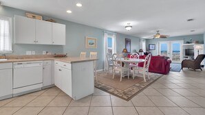 A spacious kitchen with white cabinetry, a dining area with a red sofa, and a ceiling fan.