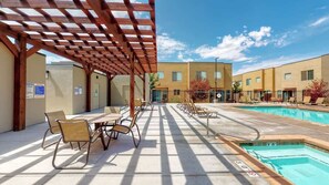 Un área de piscina al aire libre con zona de estar soleada y un porche cubierto.