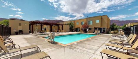 A pool area with lounge chairs and a building in the background.