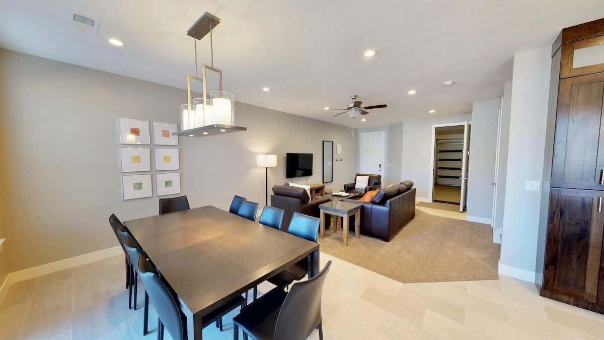 A modern living room with a dining area, a sofa set, a TV, and a ceiling fan.