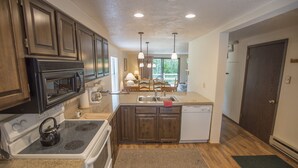 A kitchen with wooden cabinets, a stove, a microwave, a sink, and a dishwasher. - Great 2 bed townhouse. This is the best location in Ketchum! (Ketchum)