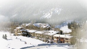 A snow-covered resort with multiple buildings, ski slopes, and a mountainous backdrop. - Great 2 bed townhouse. This is the best location in Ketchum! (Ketchum)