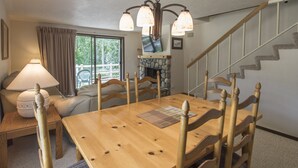 A dining area with a wooden table and chairs, a lamp, and a view of a staircase. - Great 2 bed townhouse. This is the best location in Ketchum! (Ketchum)