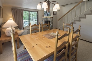 Enjoy meals in this cozy dining area with a fireplace, TV, and large window offering a view of the surrounding greenery.