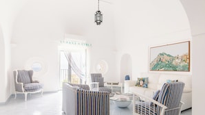 Ein helles, geräumiges Wohnzimmer mit gestreifter Möblierung, einem weißen Sofa und einem großen Gemälde an der Wand.
