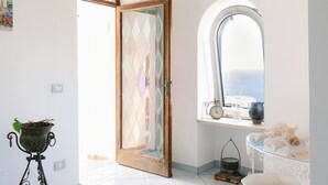 Ein Zimmer mit einer großen Holzt ür, einem Fenster mit Blick, einem Blumentopf und einem Regal mit Dekoration.