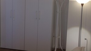 Un dormitorio con cama, armario y lámpara de pie.