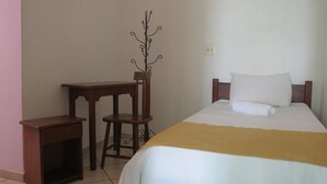 A bedroom with a bed, a bedside table, a chair, and a coat rack. - La Villa Hotel (Cordeirópolis)